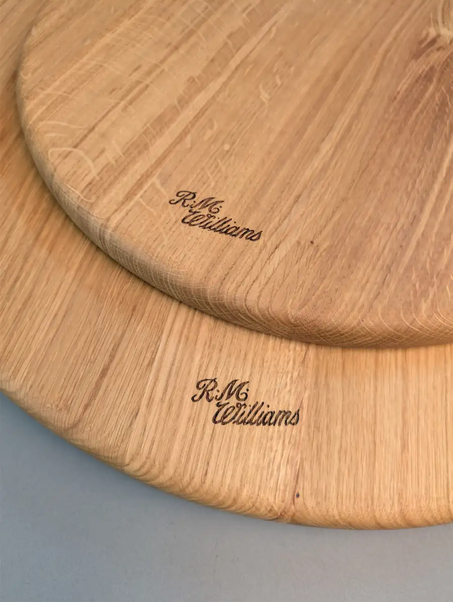 Two large round wooden serving boards with custom laser-engraved R.M. Williams logos, crafted in Edinburgh.